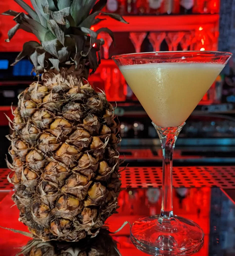 A pineapple martini with a glass next to it.