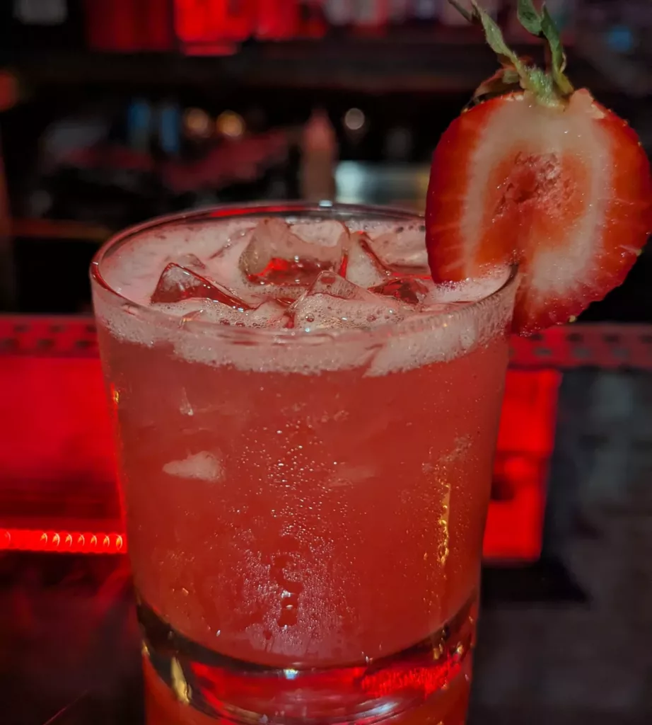 A cocktail with a strawberry garnish is served at the bar.