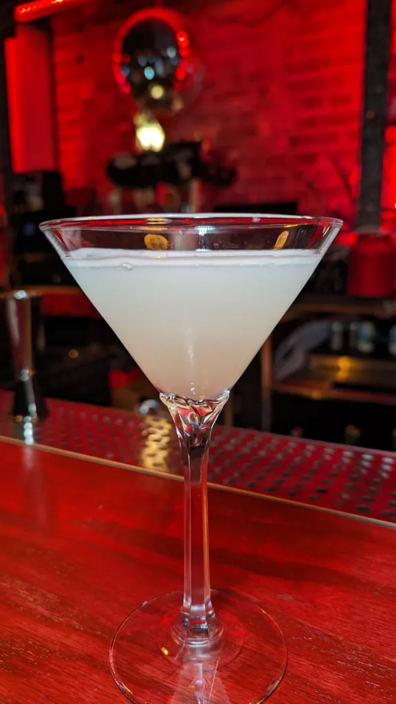 A martini sits in a glass on a bar.