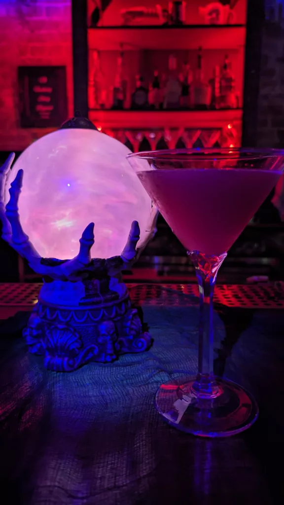 A martini is sitting on a table next to a lamp at the bar.
