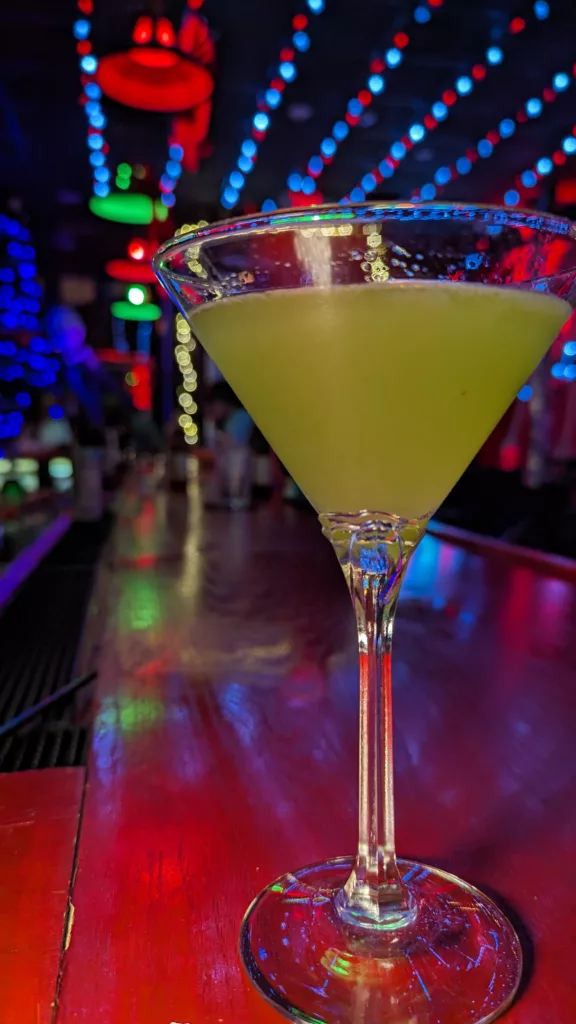 A green martini in a glass at a bar.