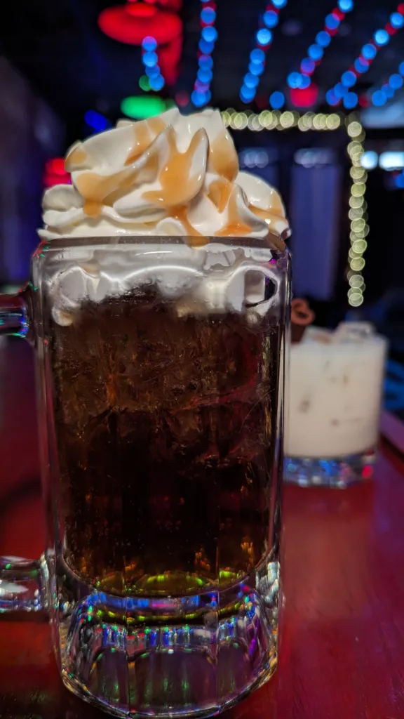 A glass of iced coffee with whipped cream on top.