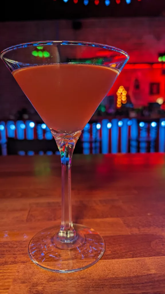 A cocktail is sitting on top of a wooden bar.