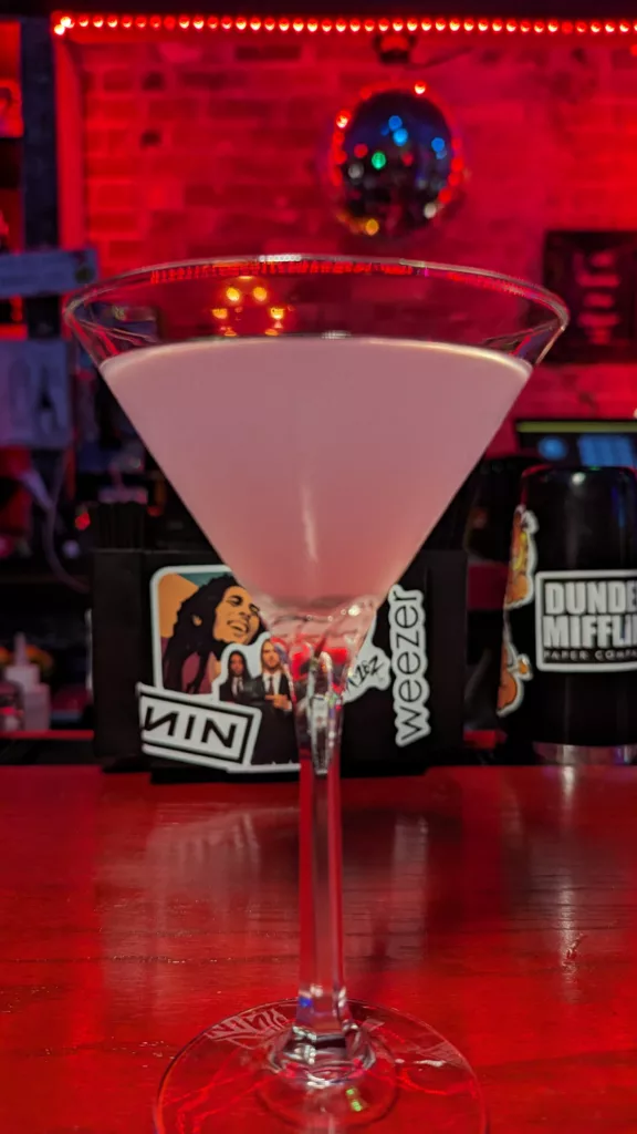 A pink martini in a glass on the bar.